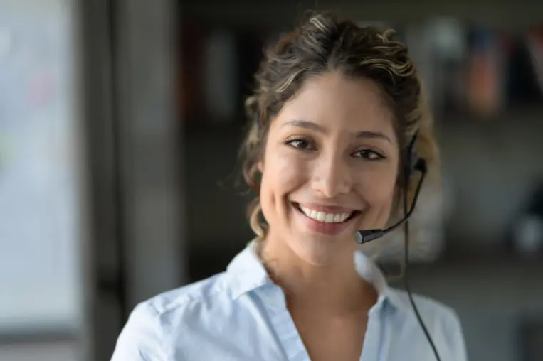 Sales Assistant Symbolbild: Eine junge Frau mit Headset lächelt freundlich in die Kamera