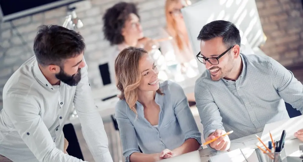 Das Bild zeigt eine Junior Sales Managerin im Austausch mit zwei Teamkollegen.